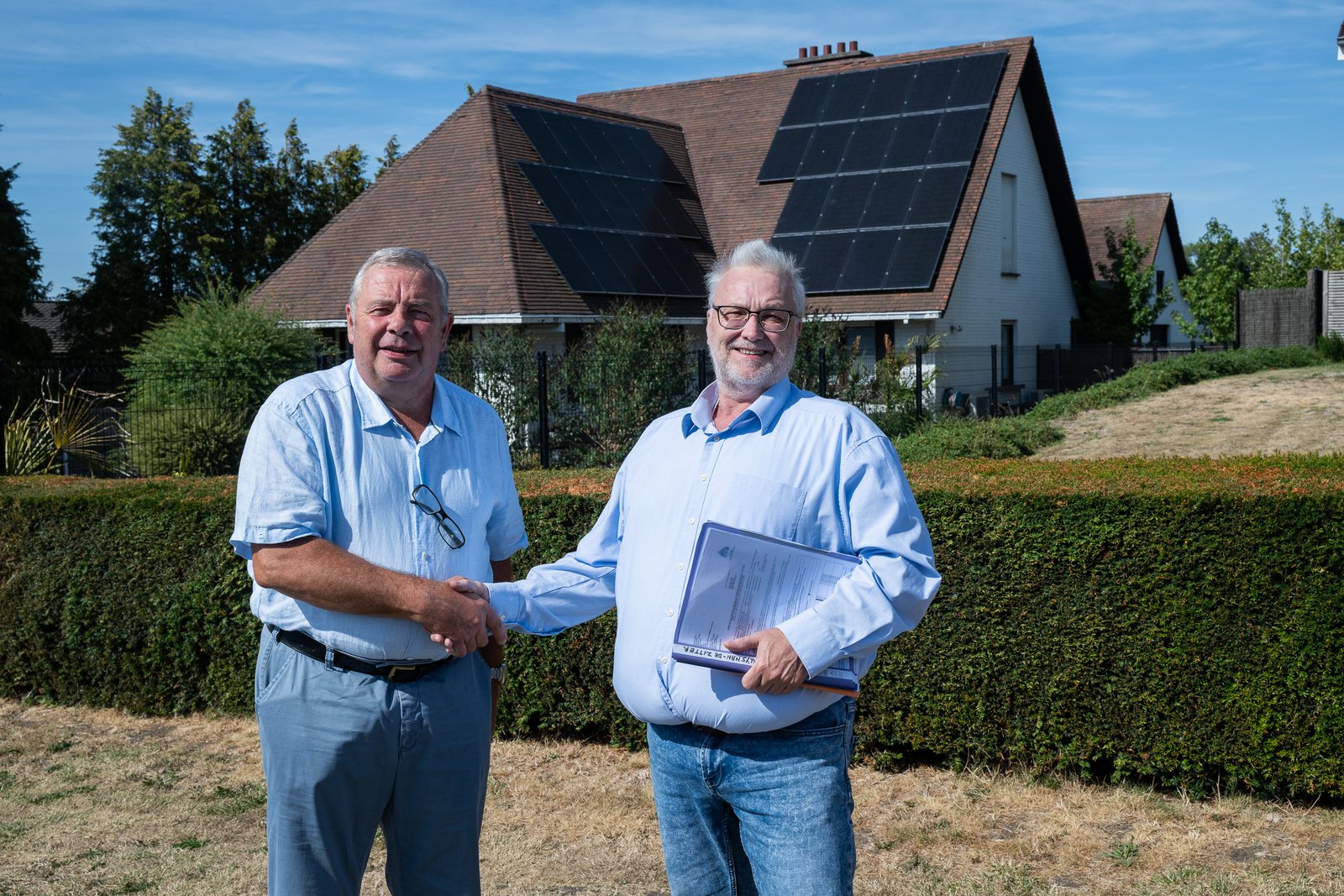 Koen van ADW geeft Jean Luc Gheysens een hand voor diens woning met zonnepanelen in Ronse