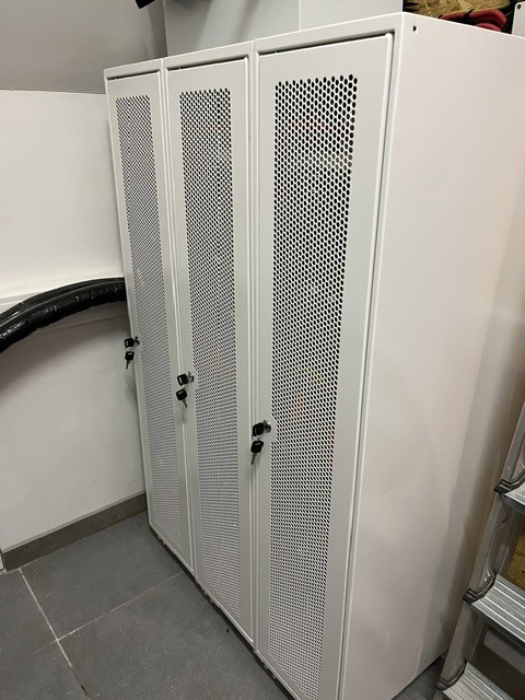Closed, lockable battery cabinet with perforated doors in a technical room