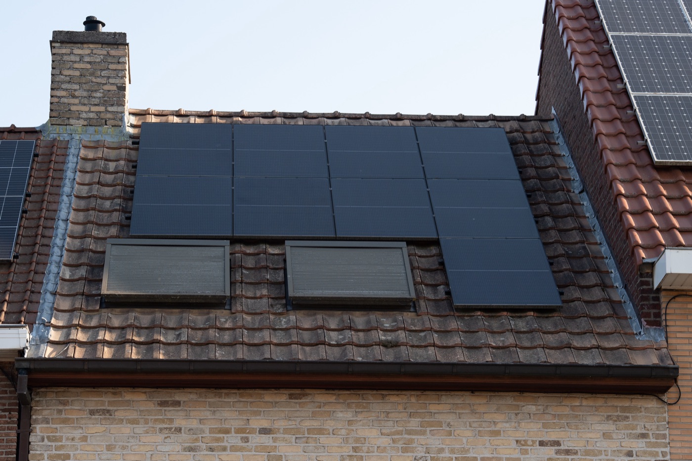 Solar panels beside two roof windows on a tiled roof