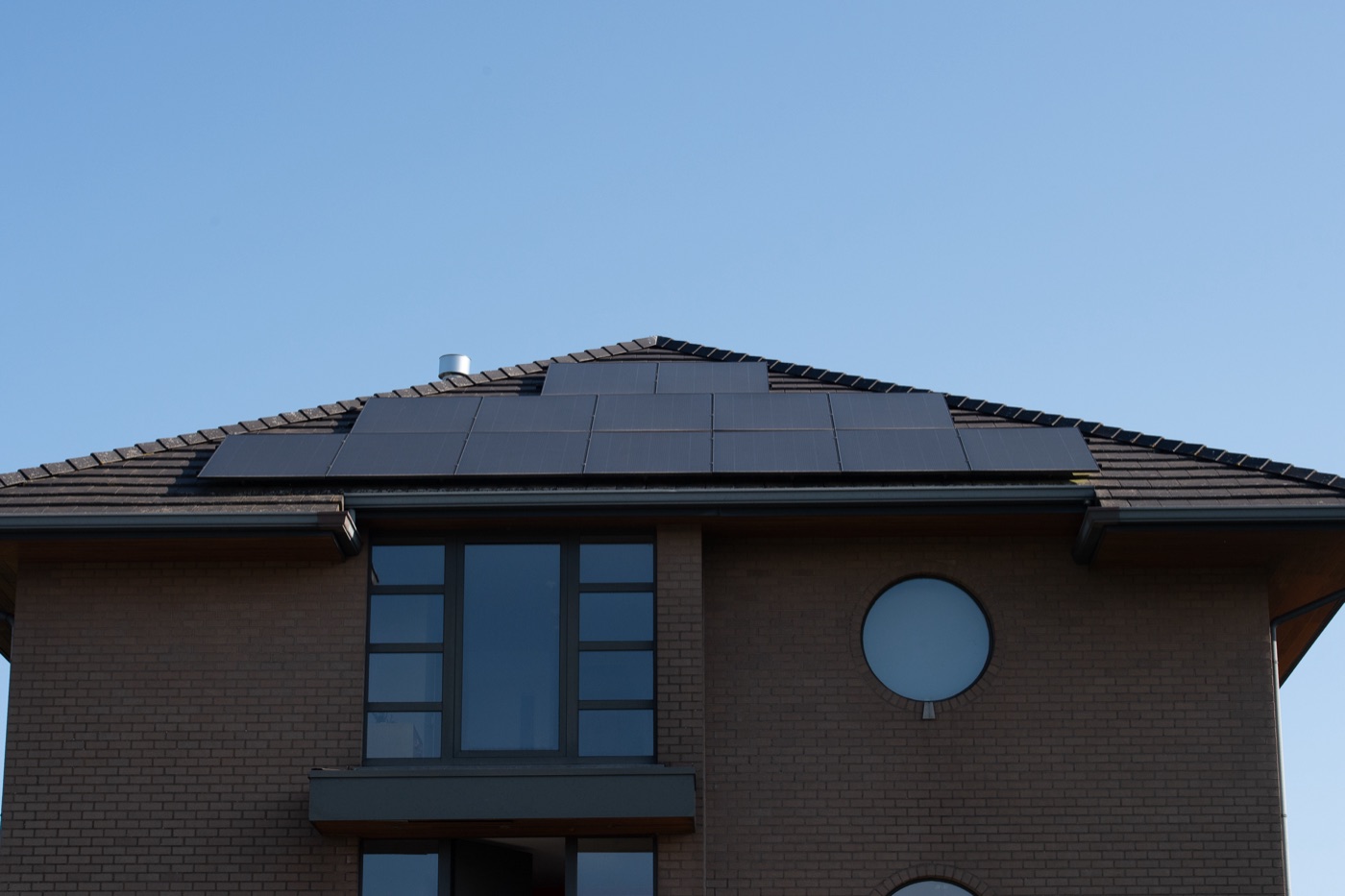 Solar panels on a brick home under a blue sky
