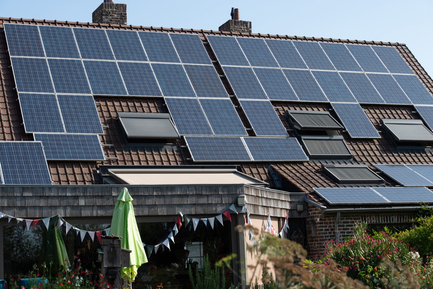 Large solar array across two roof planes of a house with a garden