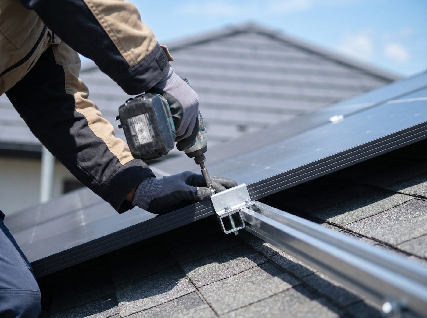 Technician installing a black solar panel on a rooftop rail